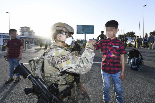 공군 최정예 특수부대 요원인 공정통제사가 25일 아프가니스탄 카불공항에서 한국으로 이송될 아프간 현지 조력자 자녀와 인사하고 있다.   [공군 제공]